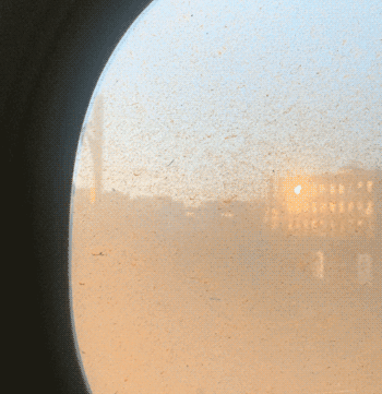 gif of the sun's reflection moving across a building through an Amtrak train window